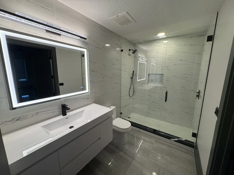 Floating white vanity, illuminated mirror and shower with veined white tile