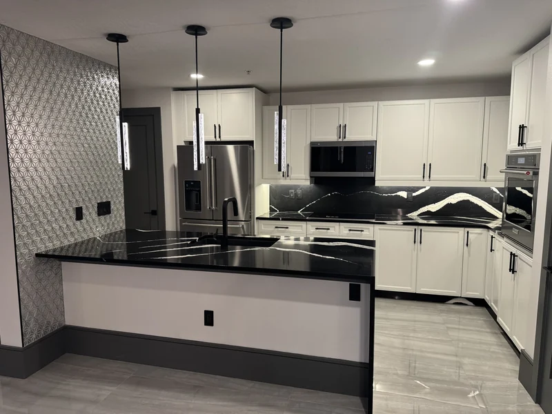 White kitchen cabinetry, dark counters and a contrasting veined backsplash