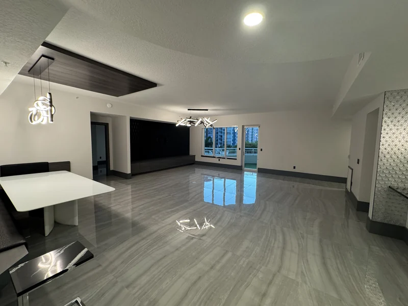 Open living and dining space with pale tile flooring and a dark feature wall