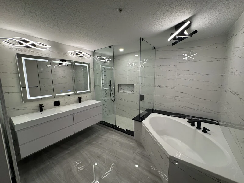 Double vanity, soaking tub and glass shower surrounded by marble-look tile