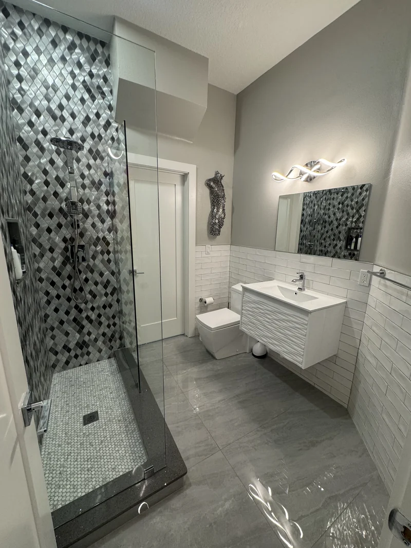 Floating white vanity alongside a shower with geometric patterned tile