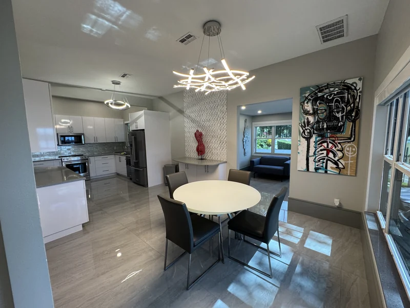Open kitchen and dining area with white cabinetry and large gray floor tiles