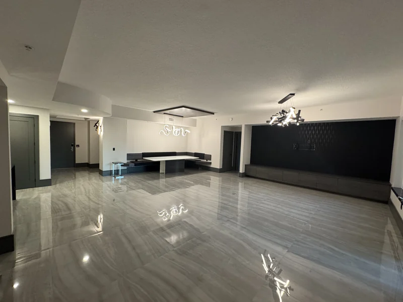 Open living space with large gray floor tiles and a dark feature wall