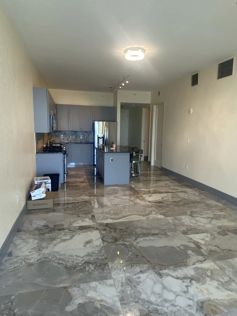 Open living area and kitchen with large veined gray floor tiles