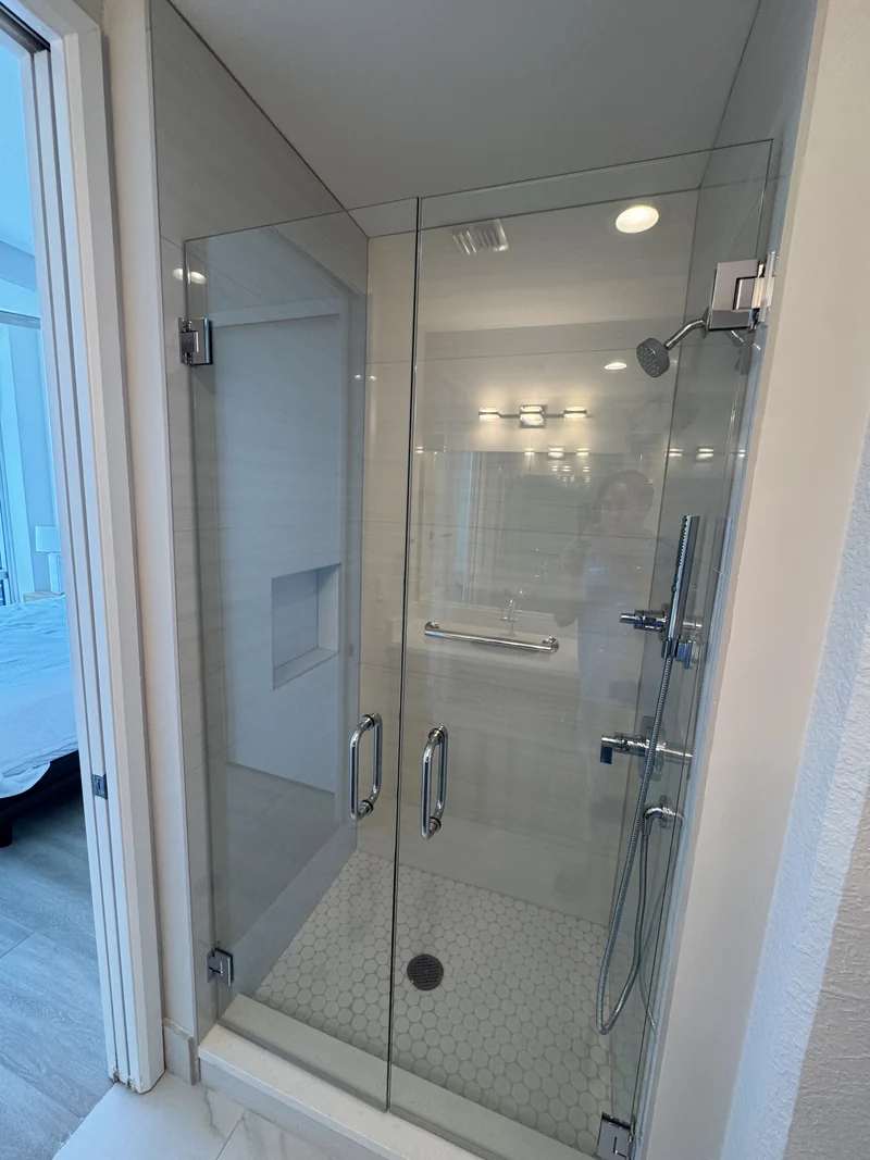 Glass shower enclosure with white wall tile and a round mosaic floor