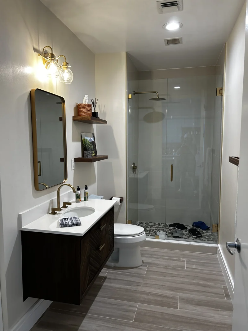 Dark wood vanity, pale countertop and glass shower over wood-look tile flooring