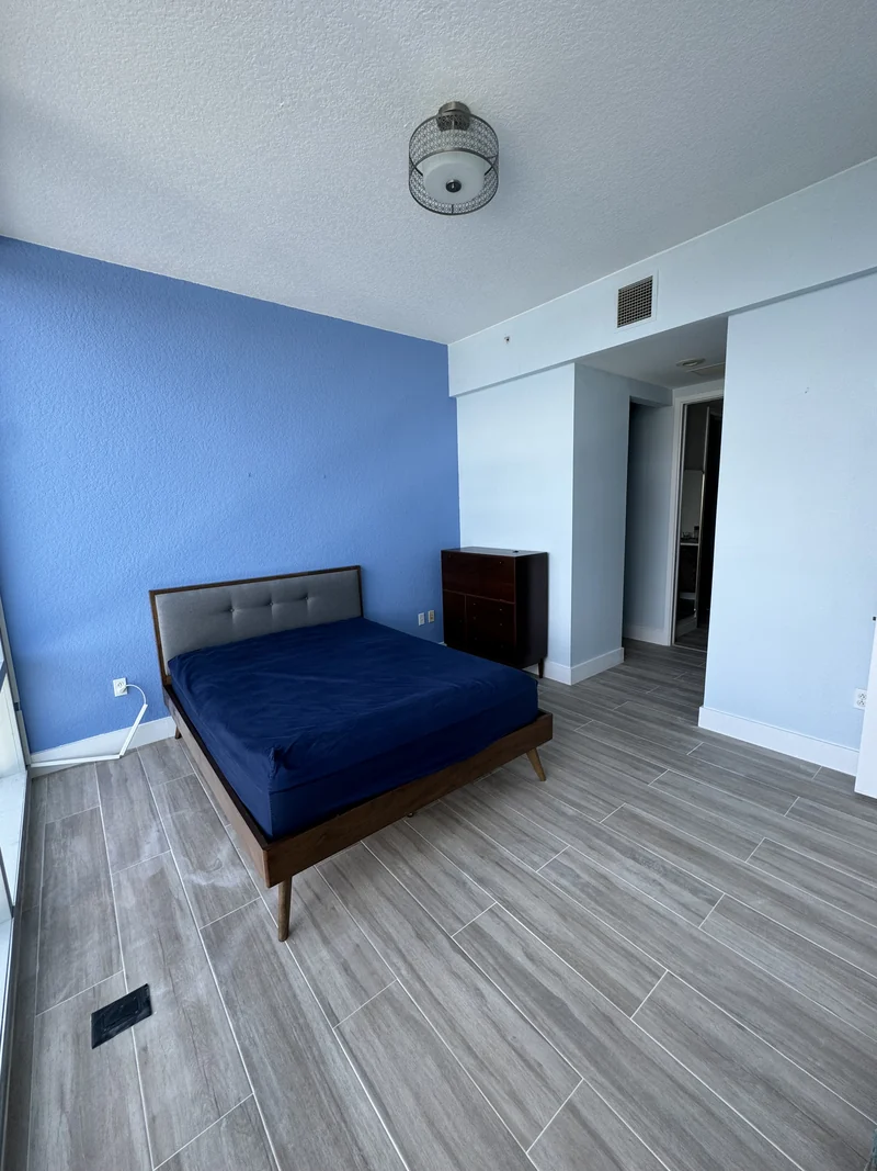 Bedroom with a blue accent wall and wood-look tile flooring