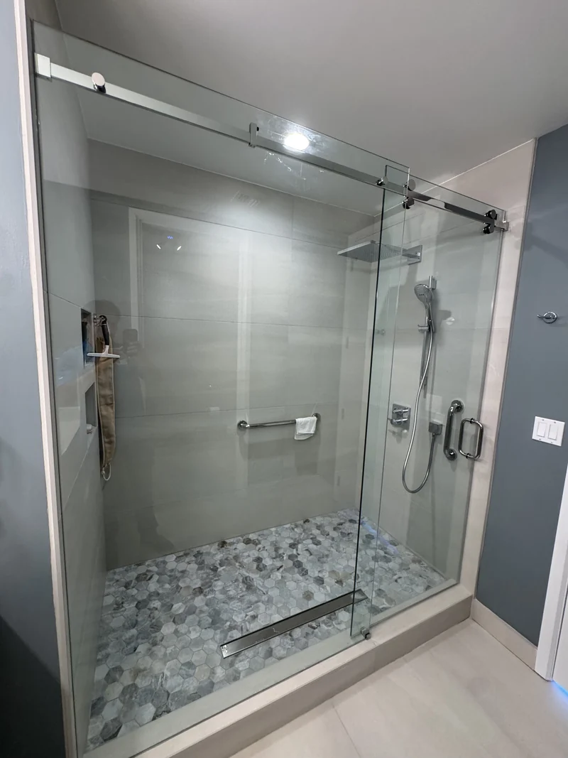 Sliding glass shower enclosure with gray walls, a recessed niche and patterned floor tile