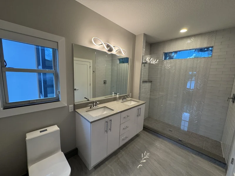White vanity and glass shower with a high window and pale wall tile