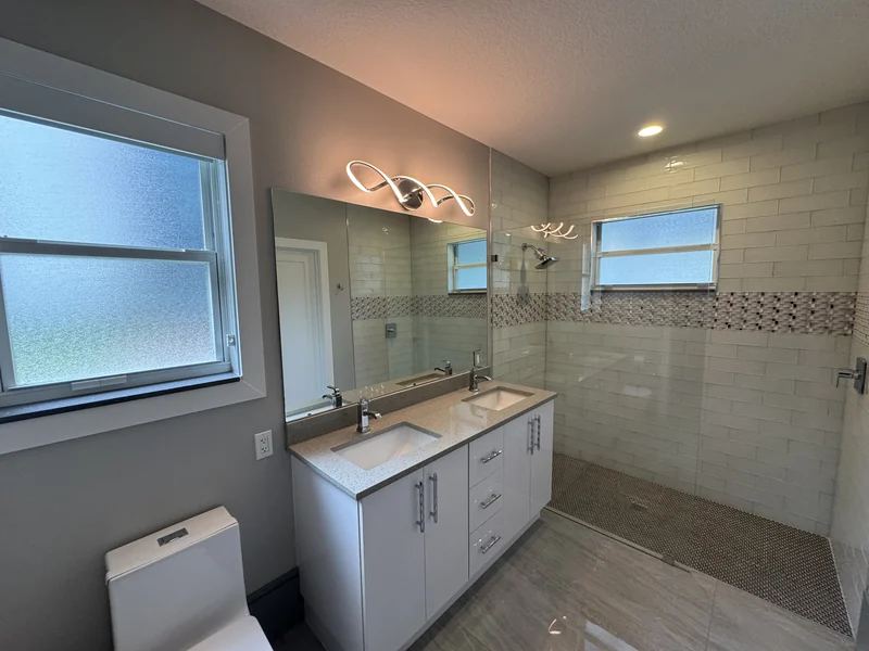Double vanity and glass shower with a patterned tile band