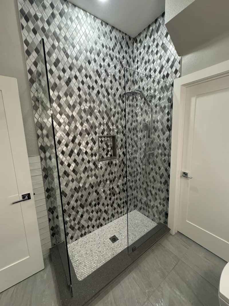 Geometric patterned shower tile, recessed niche and glass enclosure