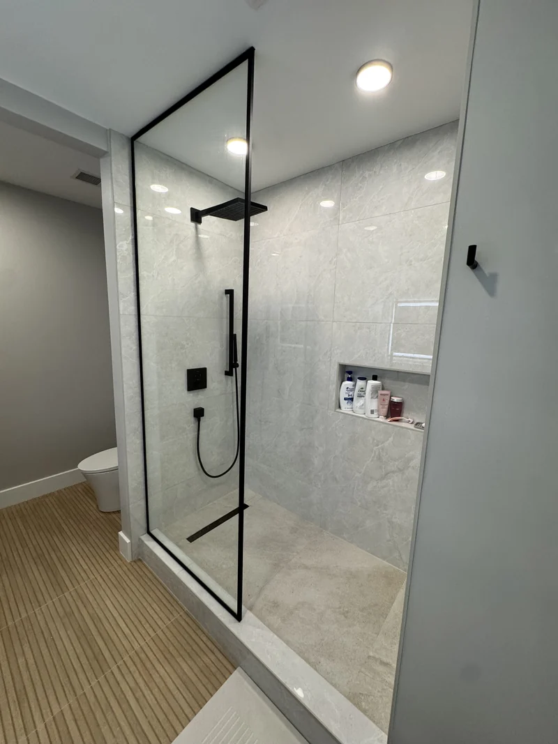 Glass shower with pale wall tile, black fittings and a recessed niche